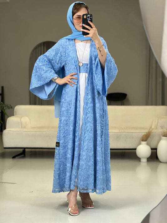 A woman wearing a baby blue floral dantel abaya with wide sleeves and a matching Sheila headscarf paired with a white inner dress underneath.