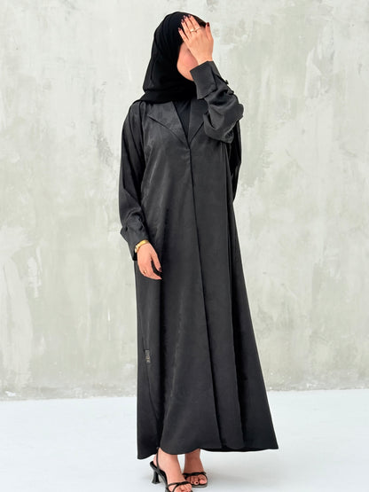 A woman wearinng a Black Floral Printed Satin Coat Abaya with lapel collar and matching Sheila