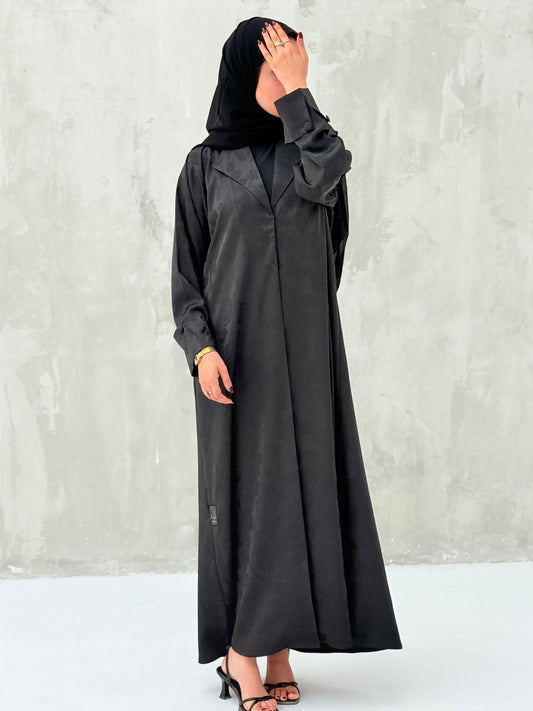 A woman wearinng a Black Floral Printed Satin Coat Abaya with lapel collar and matching Sheila