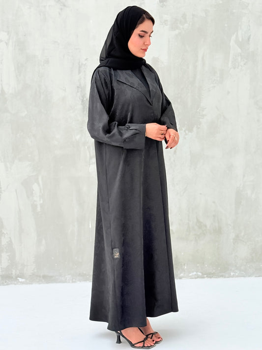 A woman wearinng a Black Floral Printed Satin Coat Abaya with lapel collar and matching Sheila