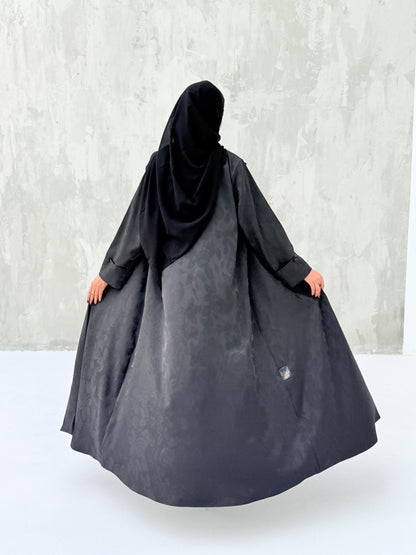 A woman wearinng a Black Floral Printed Satin Coat Abaya with lapel collar and matching Sheila