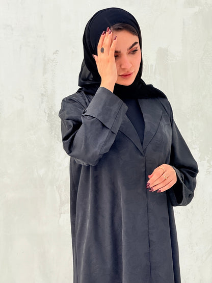 A woman wearinng a Black Floral Printed Satin Coat Abaya with lapel collar and matching Sheila