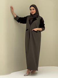 A woman wearing a olive green abaya with velvet and barbei fabric, posing against a neutral background.