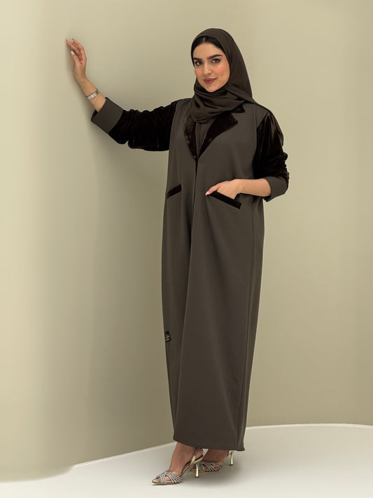 A woman wearing a olive green abaya with velvet and barbei fabric, posing against a neutral background.