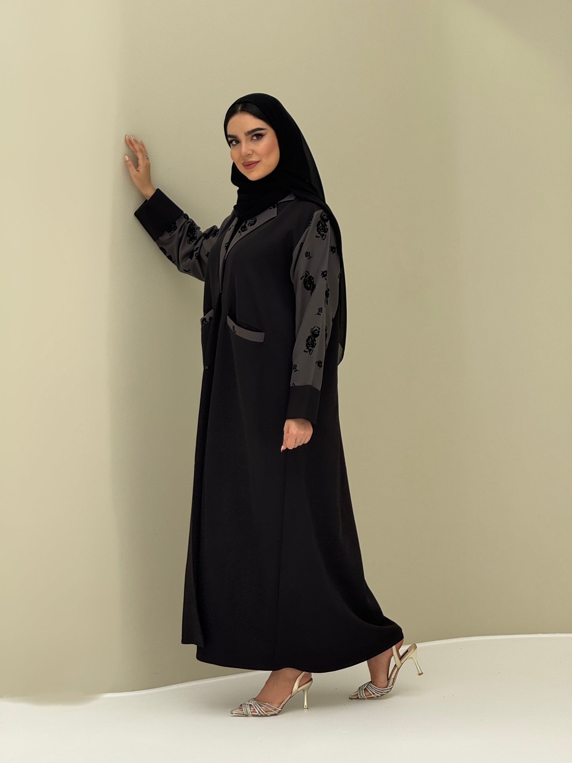 A woman wearing a Black & Grey Velvet Floral abaya with velvet and Barbie fabric.