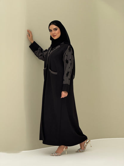 A woman wearing a Black & Grey Velvet Floral abaya with velvet and Barbie fabric.