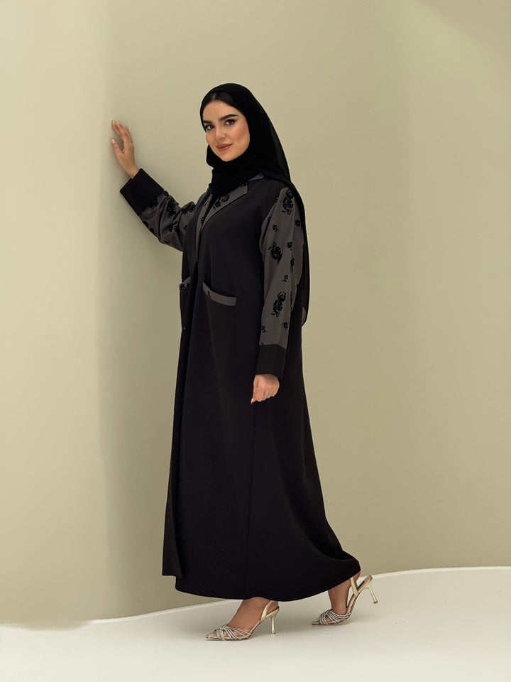 A woman wearing a Black & Grey Velvet Floral abaya with velvet and Barbie fabric.