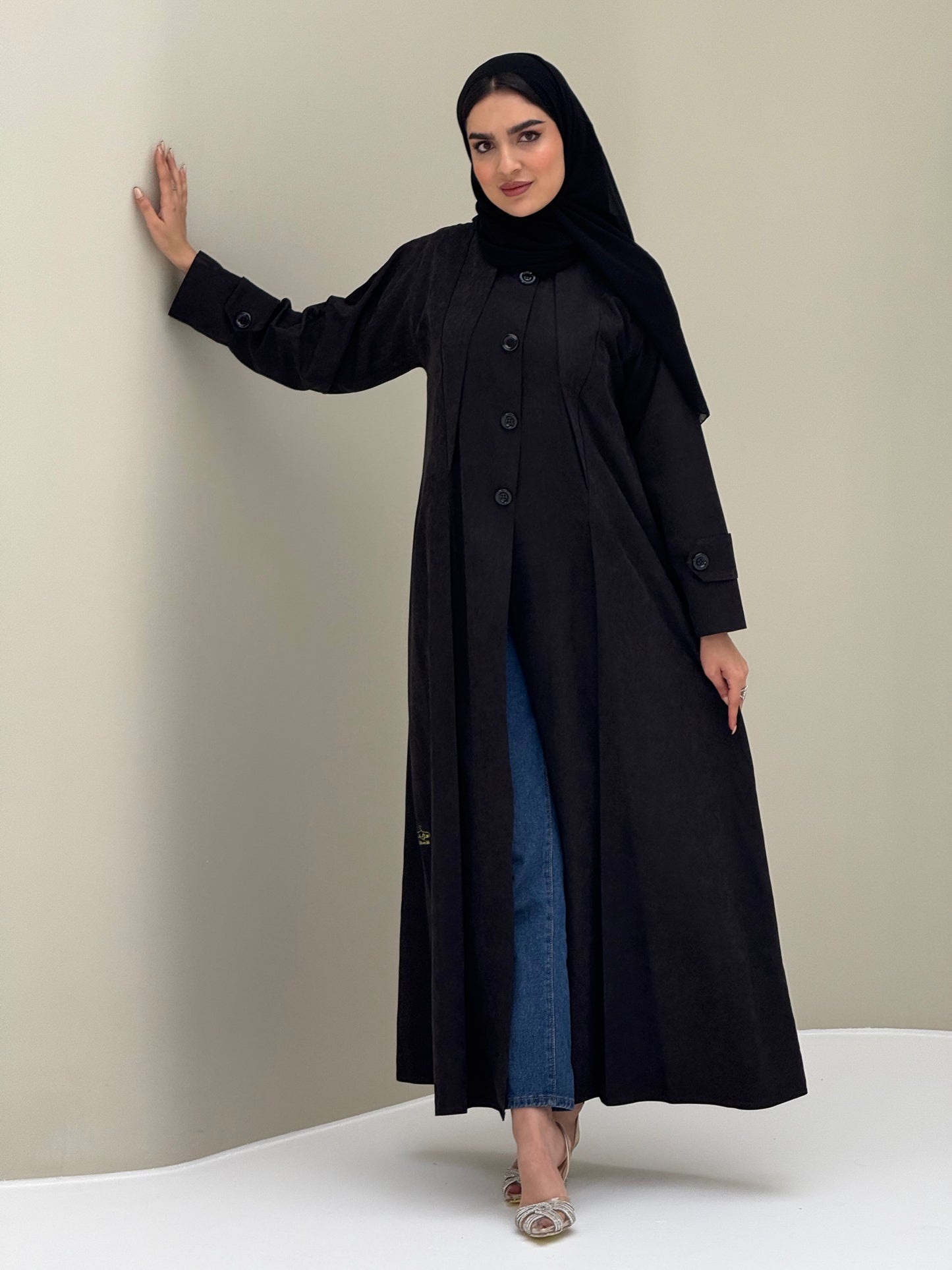 A woman wearing a black Ice Cool Coat style with round neck and panel details Button-front, vertical bodice seams, buttoned cuff tabs