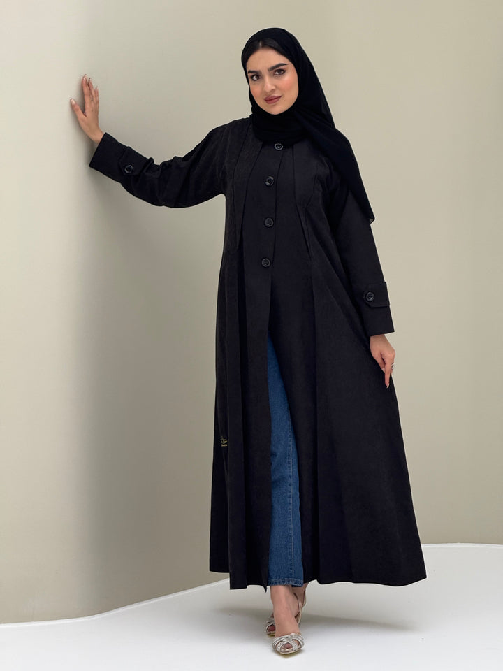A woman wearing a black Ice Cool Coat style with round neck and panel details Button-front, vertical bodice seams, buttoned cuff tabs