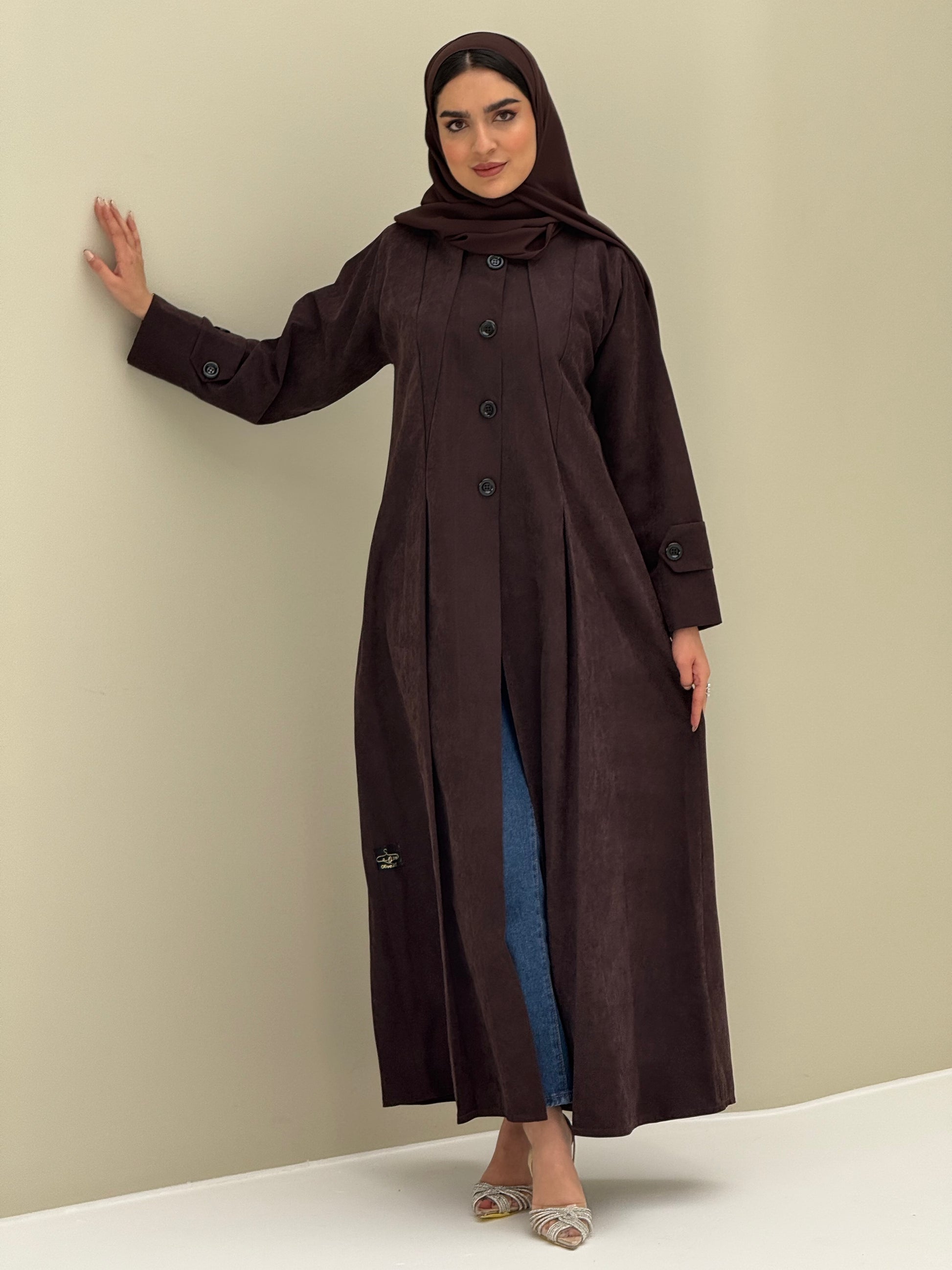 A woman wearing a dark brown Ice Cool Coat style with round neck and panel details Button-front, vertical bodice seams, buttoned cuff tabs