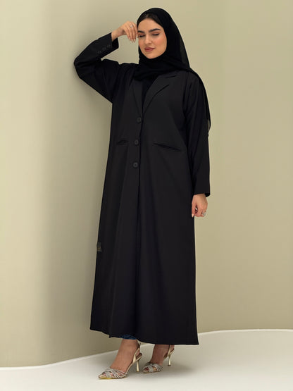 A woman wearing a black Coat style with a lapel collar, Button-front, welt pockets, buttoned cuffs, and a matching sheila