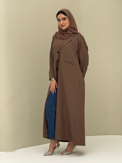 A woman wearing a brown Coat style with a lapel collar, Button-front, welt pockets, buttoned cuffs, and a matching sheila