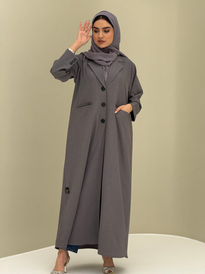 A woman wearing a dark grey Coat style with a lapel collar, Button-front, welt pockets, buttoned cuffs, and a matching sheila