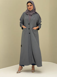 A woman wearing a light grey Coat style with a lapel collar, Button-front, welt pockets, buttoned cuffs, and a matching sheila