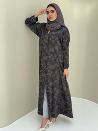 A woman wearing adaark grey abaya with a tonal floral print pattern and a matching sheila headscarf.