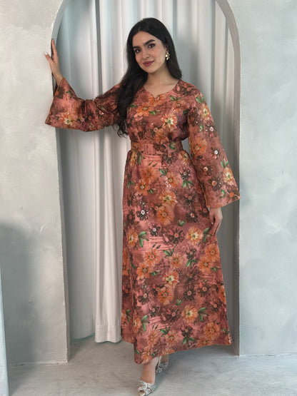 A woman wearing a copper rose Floral Print Organza with Sequin Embroidery dress with long sleeves and a round neckline.