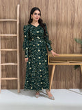 A woman sitting in a tropical setting wearing an emerald green Sheer Net Overlay with gold Floral Embroidery dress and a belt.