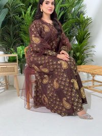 A woman seated in a garden setting, wearing an A-line brown Paisley Dress with Bishop Sleeves with gold embroidery and a netted veil.
