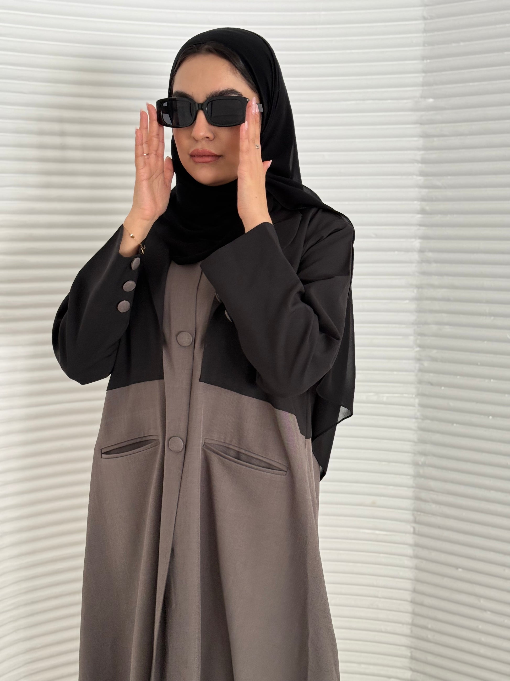A black and brown abaya, tailored from Linen, it features a coat-style collar and pockets for a structured fit.