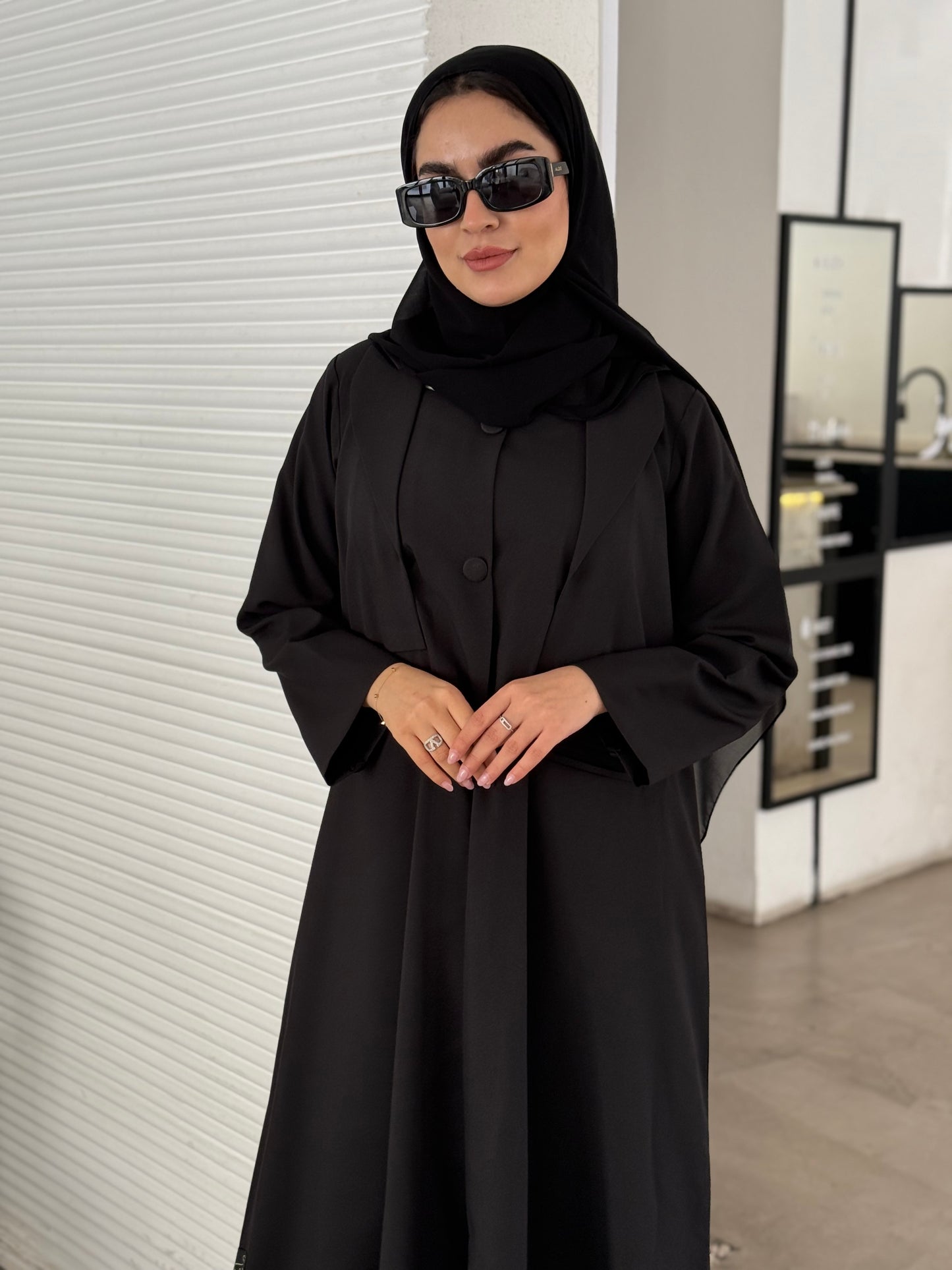 A black abaya, tailored from Linen, it features a coat-style collar and pockets for a structured fit.
