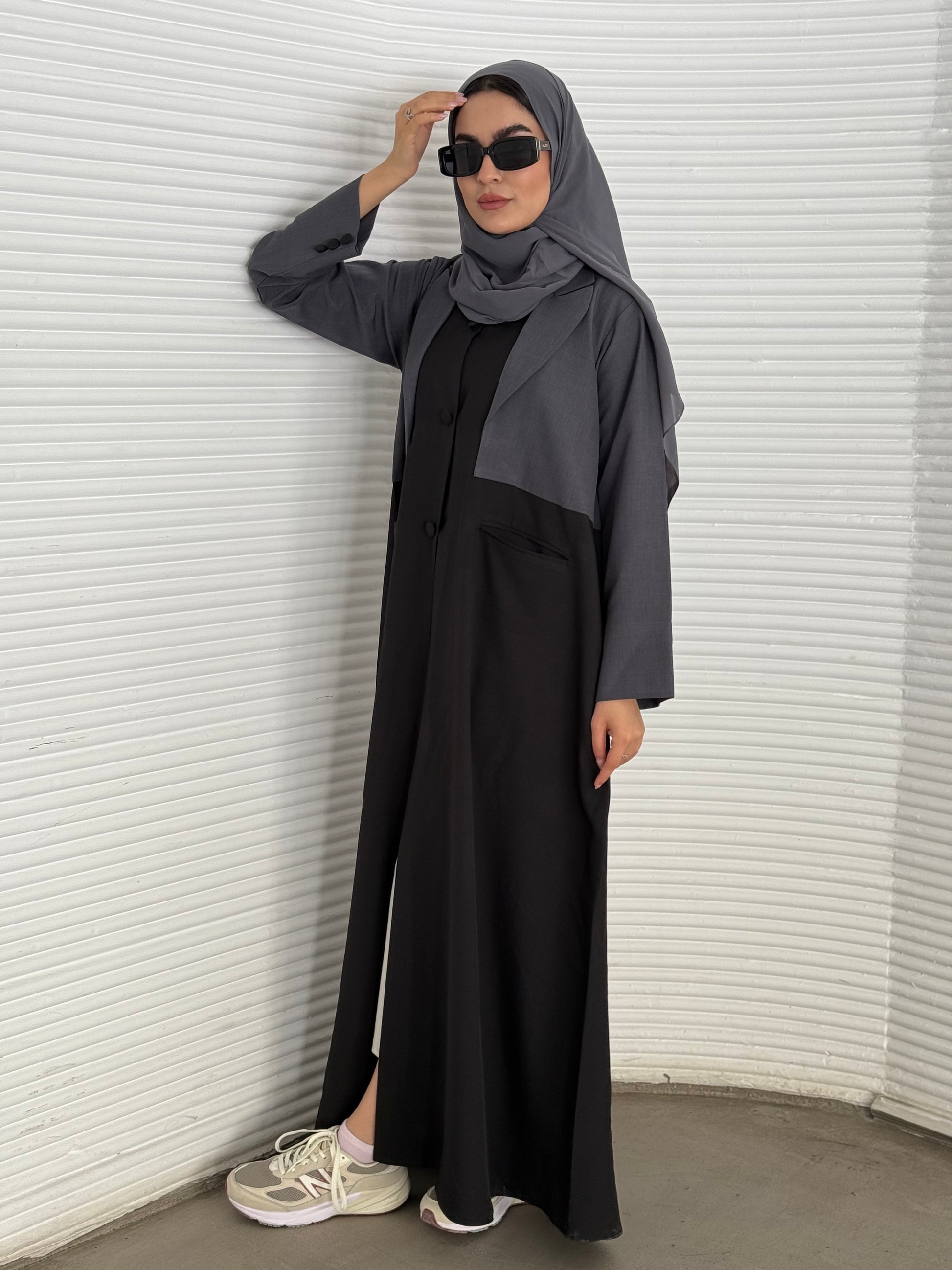 A black and grey abaya, tailored from Linen, it features a coat-style collar and pockets for a structured fit.