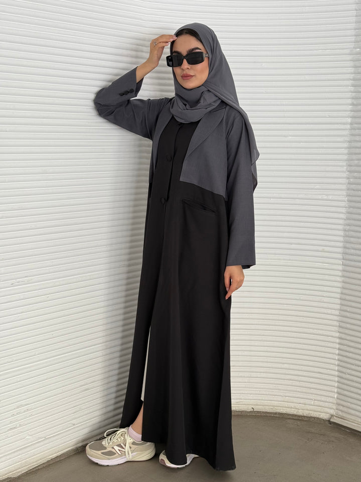 A black and grey abaya, tailored from Linen, it features a coat-style collar and pockets for a structured fit.