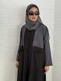 A black and grey abaya, tailored from Linen, it features a coat-style collar and pockets for a structured fit.