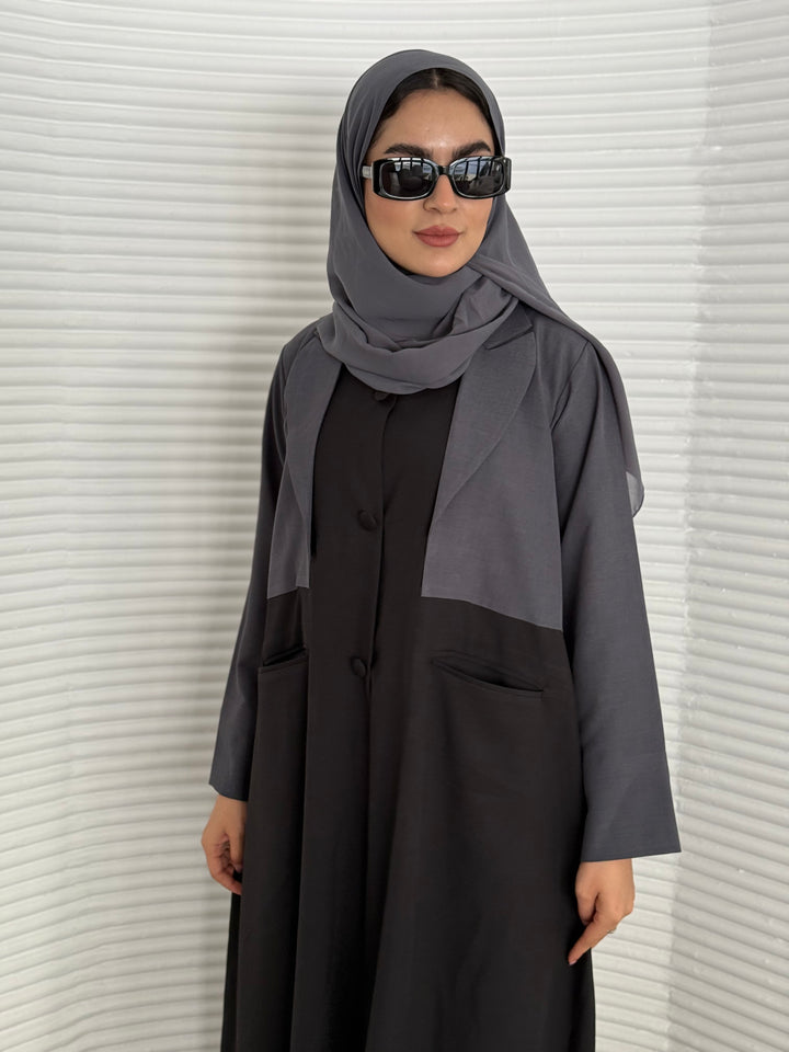 A black and grey abaya, tailored from Linen, it features a coat-style collar and pockets for a structured fit.