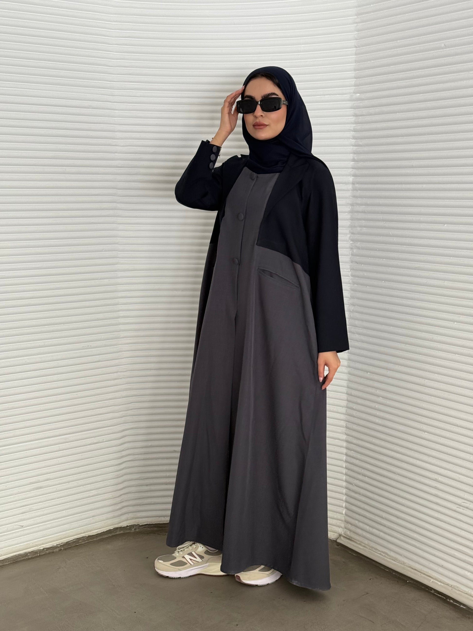 A navy blue and grey abaya, tailored from Linen, it features a coat-style collar and pockets for a structured fit.