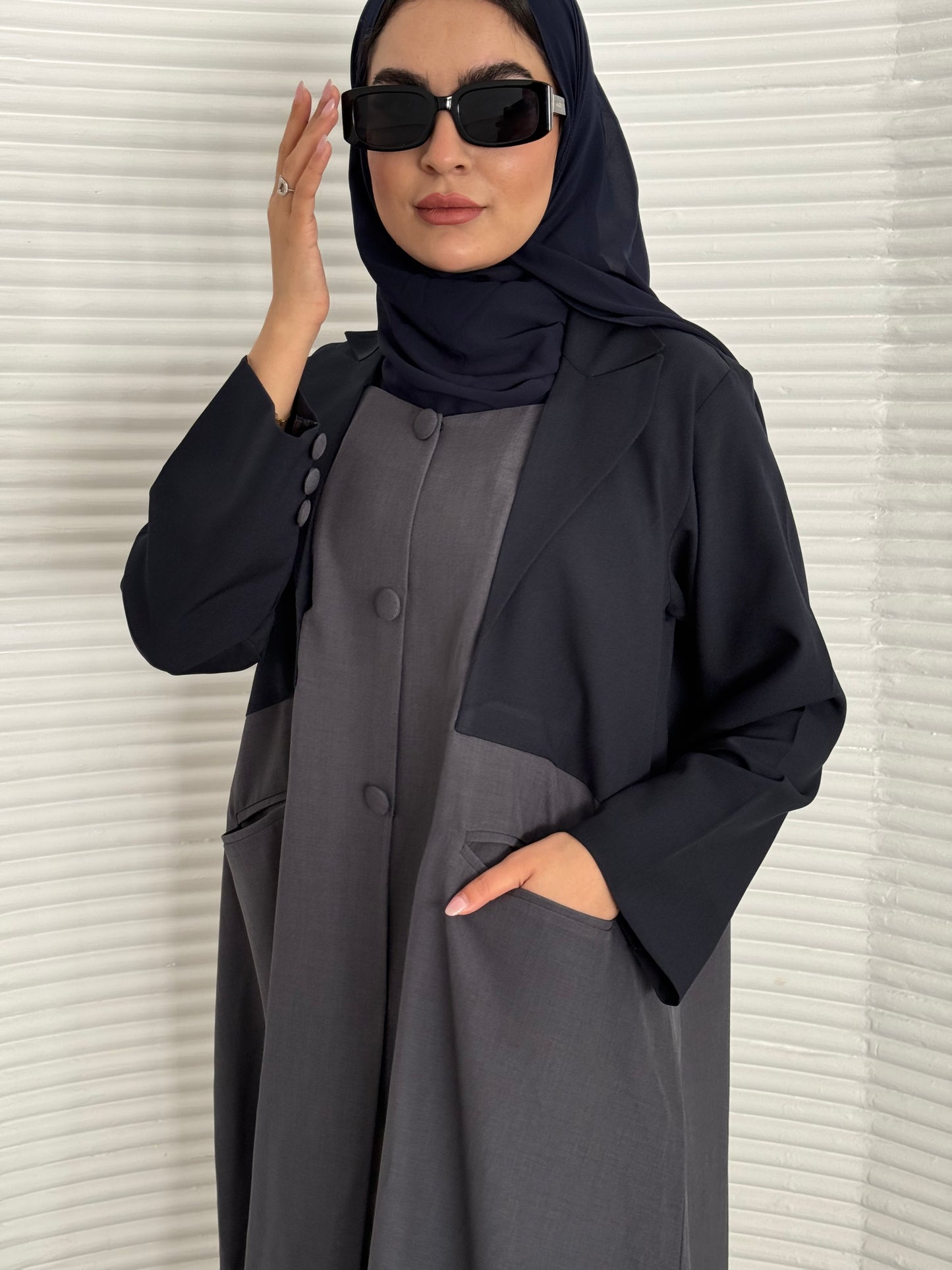 A navy blue and grey abaya, tailored from Linen, it features a coat-style collar and pockets for a structured fit.