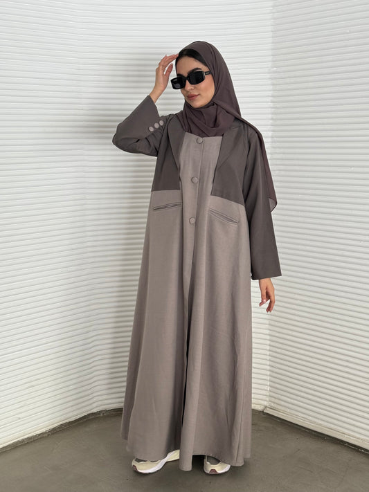 A taupe and beige abaya, tailored from Linen, it features a coat-style collar and pockets for a structured fit.