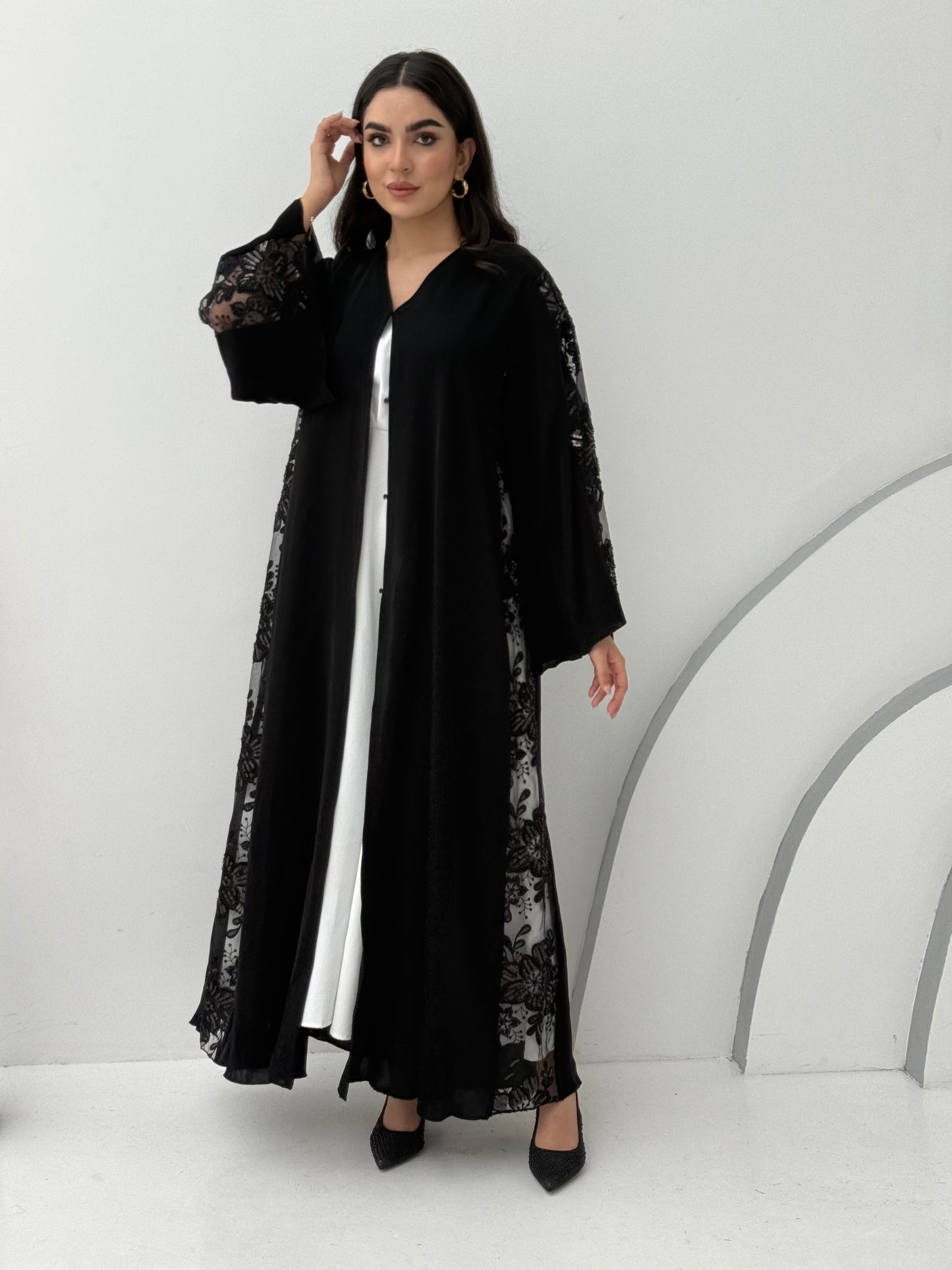 A black nida premium fabric abaya, that has floral lace (dantel) panel run vertically down the sides and sleeves.Perfect for Eid and special events.