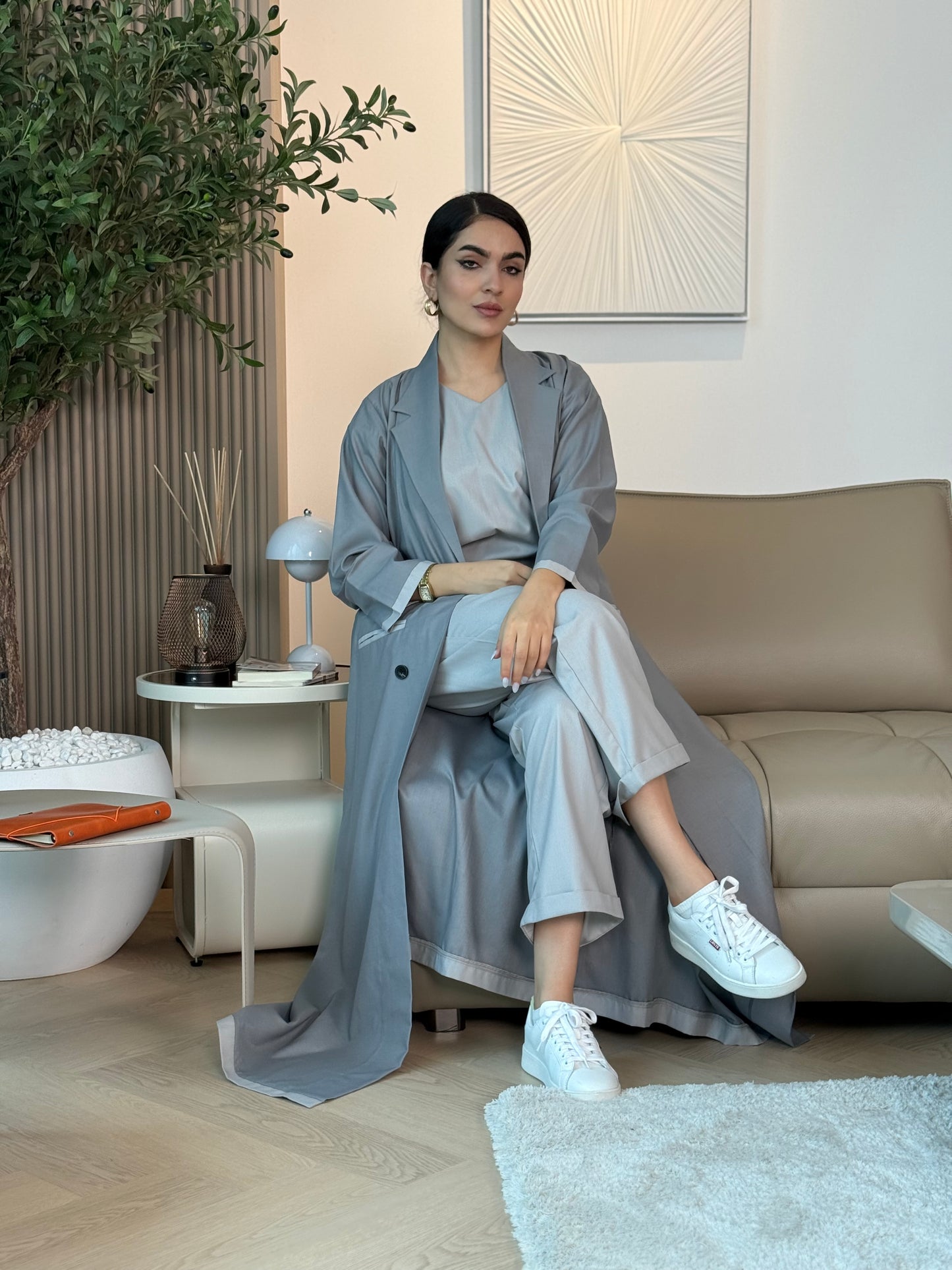 Woman sitting on a couch in a modern living room wearing a Blue-Grey Linen Abaya Set