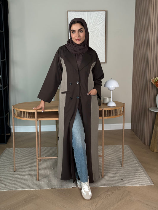 Woman in a long dark brown Linen Coat Abaya with a matching sheila standing in a room with a desk and chair.