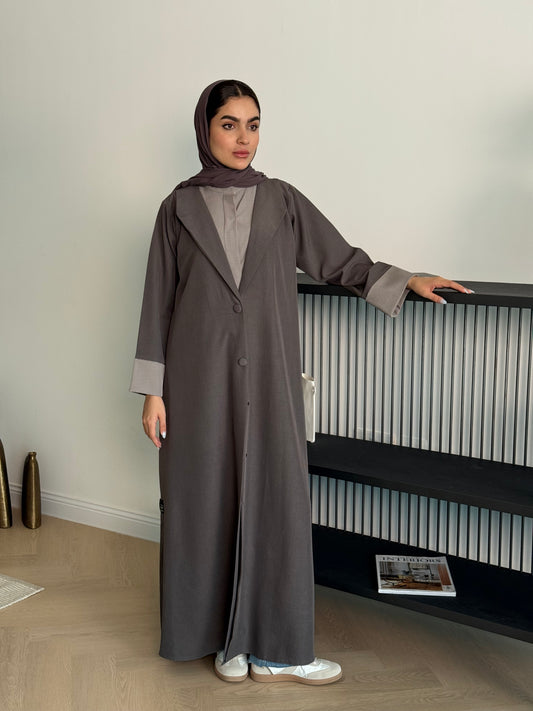 Woman wearing a long Brown Linen Coat Abaya with matching sheila standing indoors.