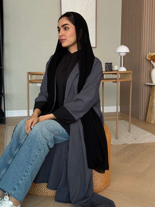 Woman sitting on a chair wearing a Dark Grey Linen Coat Abaya in an indoor setting with a black sheila 