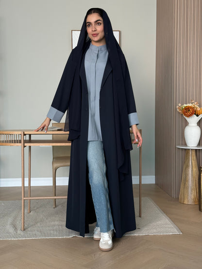 A woman wearing a long navy blue Linen Coat Abaya with a matching sheila headscarf in a room.