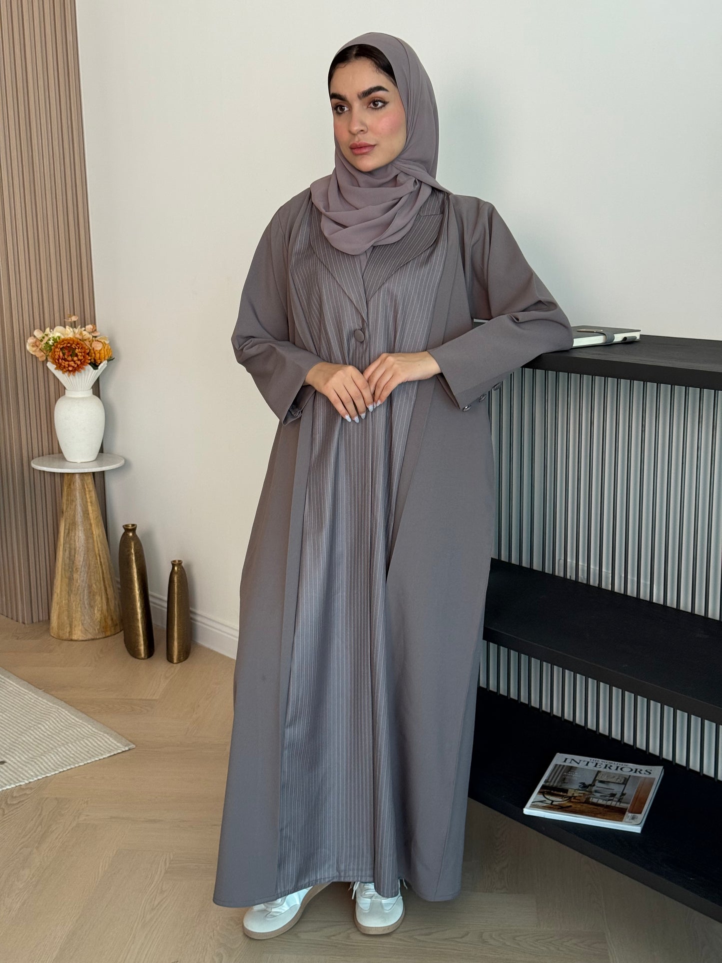 Woman in a long Mauve Grey Pinstripe Linen Abaya and a matching sheila standing in a room 