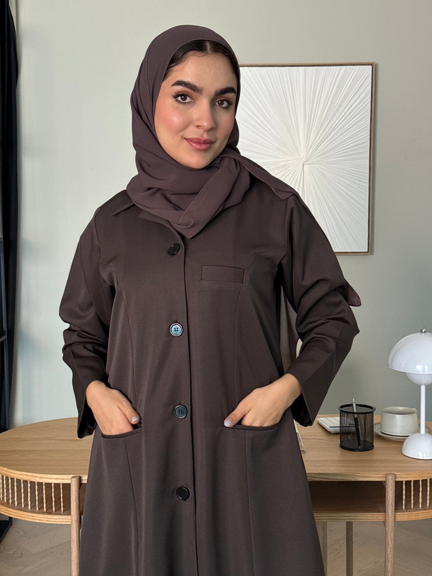 Woman wearing a Chocolate Brown Linen Pocket Abaya coat  with a matching sheila in an indoor setting