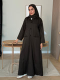 Woman wearing a dark green Linen Pocket Abaya coat  with a matching sheila in an indoor setting
