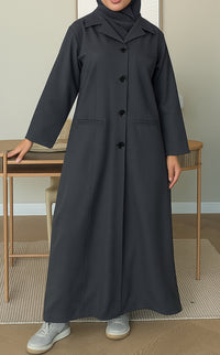 Woman wearing a dark grey Linen Pocket Abaya coat  with a matching sheila in an indoor setting