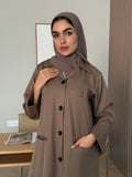 Woman wearing a brown Linen Pocket Abaya coat  with a matching sheila in an indoor setting