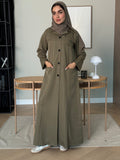 Woman wearing an olive green Linen Pocket Abaya coat  with a matching sheila in an indoor setting