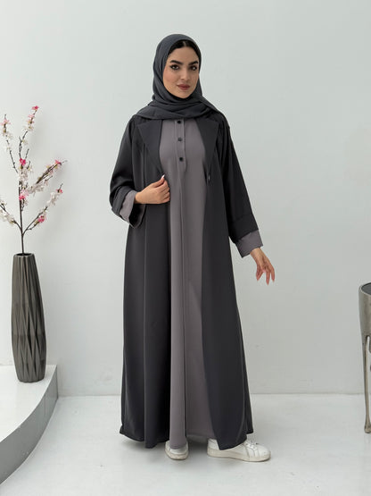 Woman wearing a long Dark Grey & Light Grey Abaya with a matching sheila in a minimalistic setting.