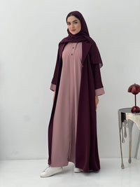 Woman wearing a long, Maroon and Dusty Pink Abaya with a matching sheila hijab on a white background