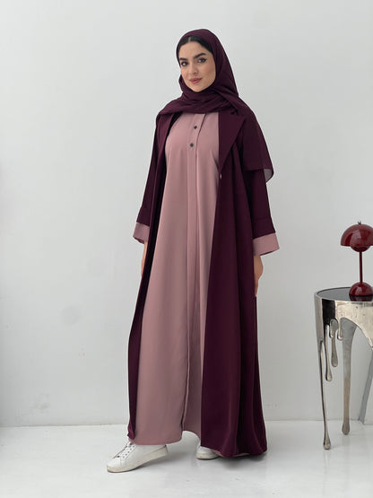 Woman wearing a long, Maroon and Dusty Pink Abaya with a matching sheila hijab on a white background