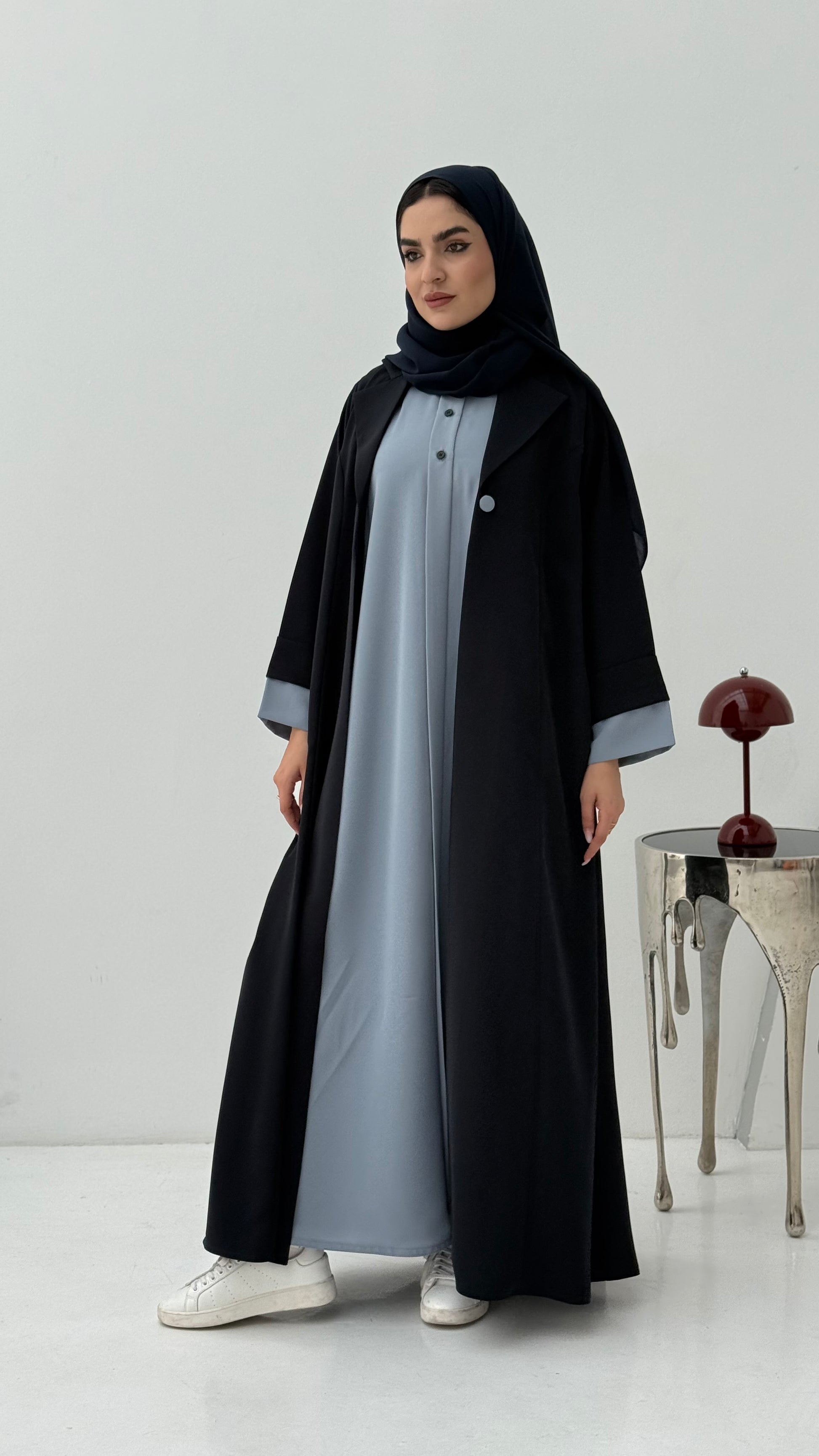 Woman wearing a Navy Blue Abaya with a light gray overlay on a white background