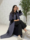 Woman wearing a long Steel Grey Shamwa Abaya Set in an indoor setting with a plant in the background