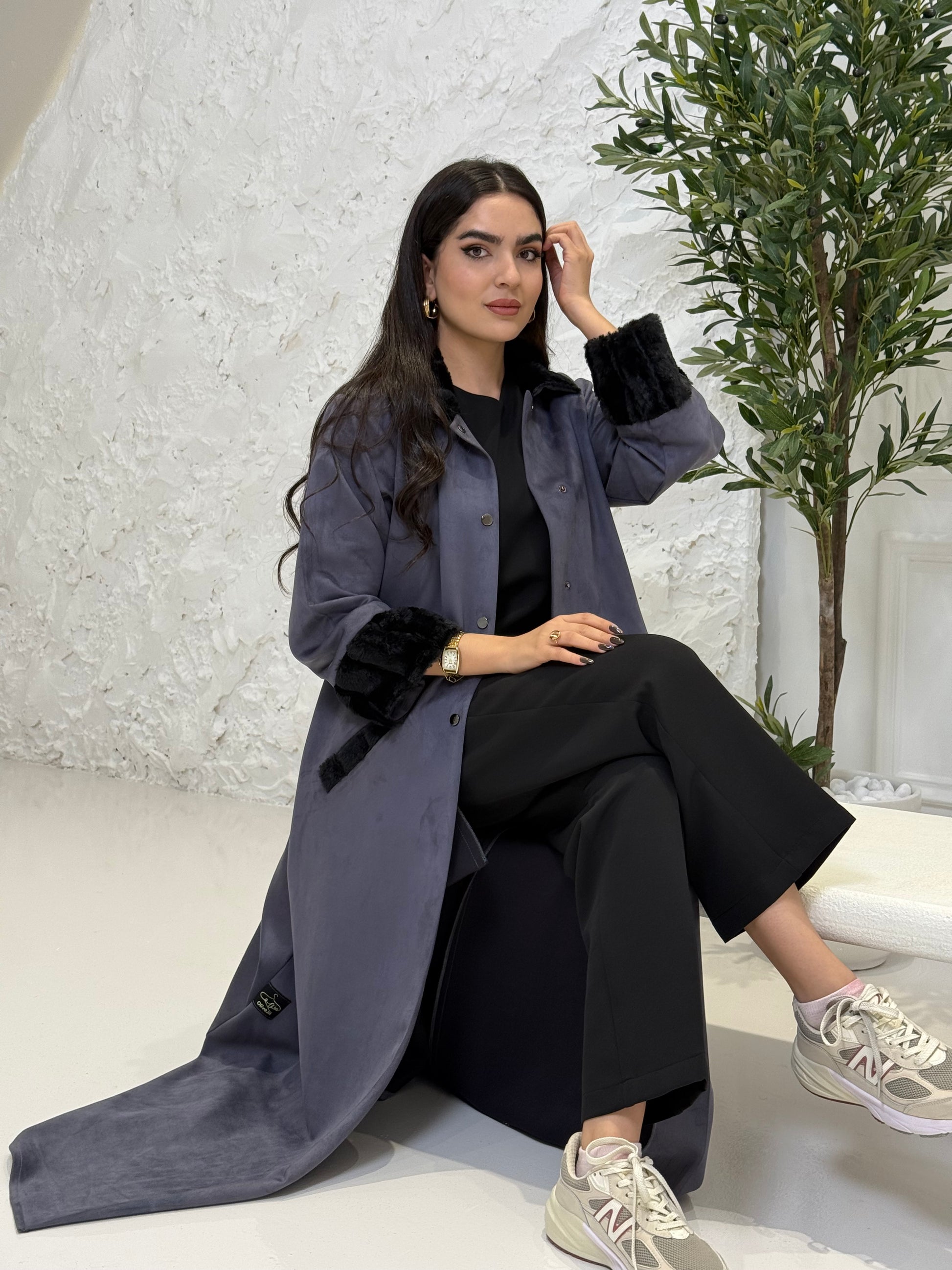 Woman wearing a long Steel Grey Shamwa Abaya Set in an indoor setting with a plant in the background