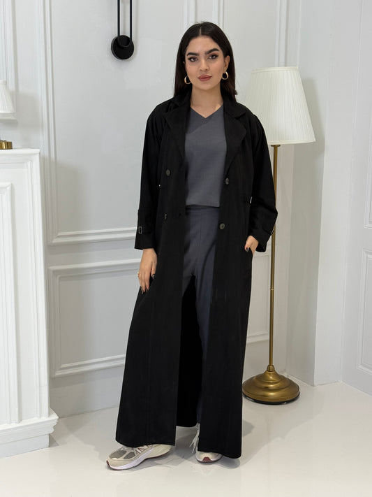 Woman wearing a Black Shamwa Trench Abaya Set standing in a room with white walls and a door.